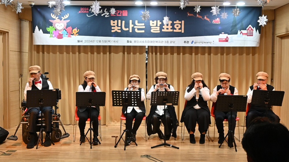 빛나는 발표회에서 장애인 7명이 하모니카를 연주하고 있다.